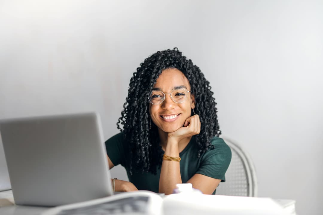 A smiling woman, sitting at a desk.