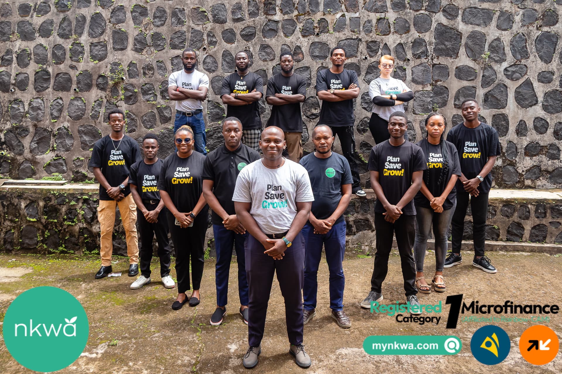 Nkwa team posing against a stone wall.